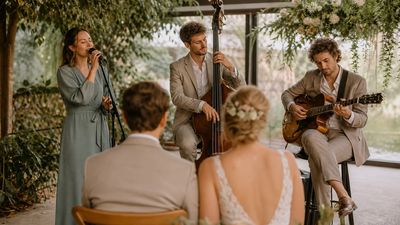 Sängerin, Kontrabassist und Gitarrist spielen vor einem Brautpaar